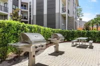 Two Stainless steel grill outdoors on a patio area with a picnic table