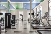 Indoor fitness center with tiled flooring, treadmill, ellipticals, and weight machines