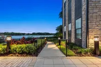 Paved lit walkway outside of apartment at night with shrubbery and railing