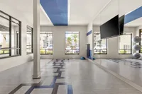 Open floor indoor fitness area with mirrors on one wall and windows
