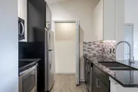 Modern kitchen with sleek stainless steel appliances, mosaic tile backsplash, and elegant black countertops.