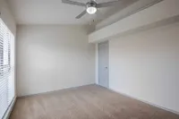 Bright and airy room with plush carpeting and elegant ceiling fan, perfect for comfort and relaxation.