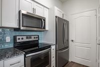 Modern kitchen with stainless steel appliances, sleek granite countertops, and stylish white cabinetry.