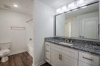 Modern bathroom featuring elegant granite countertops, soft lighting, and sleek fixtures with a spacious vanity area.