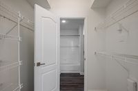 Inviting apartment interior showcasing a spacious closet with modern wire shelving adjacent to a pristine white tiled bathroom.