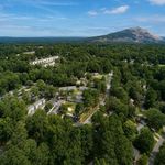 Aerial view of a serene residential community nestled amidst lush greenery with a stunning mountain backdrop, offering tranquility and scenic beauty.