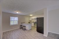 Modern open-concept kitchen and living area with sleek flooring, granite countertops, and ample natural light.