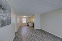 Spacious living area with modern wood flooring and natural light, featuring a cozy breakfast bar and stylish decor.