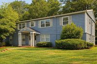 Charming blue two-story house with large windows, nestled among lush greenery for a serene and inviting atmosphere.
