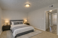 Elegant bedroom with a plush bed, stylish lamps, and a cozy ambiance; adjacent to a modern bathroom.