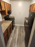 Cozy kitchen with warm wooden cabinets, sleek black appliances, and elegant laminate flooring, perfect for culinary creativity.