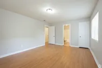 Bright and spacious bedroom with elegant wooden flooring, featuring ample natural light and an attached bathroom.