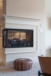 Inviting living area featuring a modern fireplace with a chic brown pouf, promising warmth and comfort.