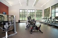 Pet-Friendly Apartments in State College, PA - Toftrees - Gym with Mirror, Equipment, Machines, High Vaulted Ceilings, Large Windows, TV, and Gym Floor