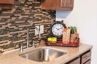 Sophisticated kitchen counter with polished granite surface, modern faucet, and decorative elements including a vintage clock and a snack display.