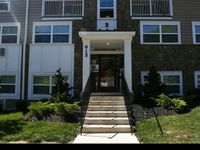 Charming two-story apartment building with stone facade, well-maintained landscaping, and large windows.
