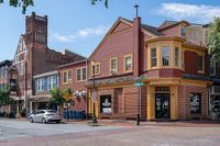 Charming corner building with historic architectural details and vibrant red and yellow accents, ideal for a stylish urban lifestyle.