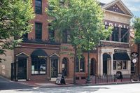 Charming brick buildings with classic architectural details and lush greenery on a lively street.