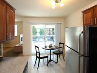 Bright and inviting kitchen with modern appliances, cozy dining area, and sliding doors leading to a scenic balcony view.