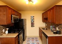 Modern kitchen with stainless steel appliances, elegant wooden cabinetry, and a vibrant backsplash, complemented by a chic wine rack display.