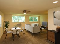 Bright and welcoming living area with modern furniture, an elegant dining set, and large windows overlooking lush greenery.