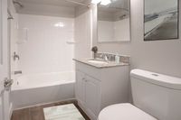 Elegant bathroom with modern fixtures, featuring a spacious bathtub, sleek vanity with granite countertop, and stylish wall art.