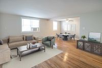 Elegant open-plan living area with plush beige sofa, chic armchair, and a stylish dining set on polished hardwood floors.