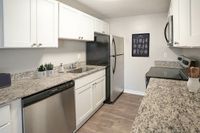 Sleek modern kitchen with granite countertops, stainless steel appliances, and elegant white cabinetry.