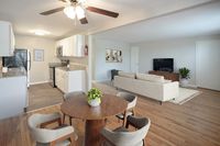Chic open-concept living space featuring a modern kitchen with stainless steel appliances, cozy dining area, and stylish living room.