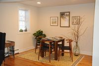Charming dining nook with modern wood furniture, accented by stylish wall art and vibrant greenery.