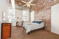 Chic loft bedroom featuring exposed brick walls, natural light, and modern decor for a cozy urban retreat.