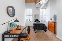 Chic and cozy bedroom with stylish desk setup, modern decor, and abundant natural light.