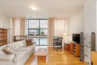 Bright and spacious living room with cozy sofa, modern desk setup, large window with natural light, and stylish decor.