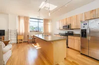 Modern kitchen with sleek stainless steel appliances, large island, and bright natural lighting.