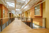 Bright and spacious corridor with wooden accents, featuring large windows and sleek metal railings.
