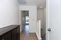 Bright and inviting hallway with sleek wooden flooring leading to a sunlit room, featuring modern design and ample natural light.