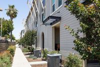 Modern apartment exterior with sleek design, abundant greenery, and spacious walkway, perfect for comfortable living.