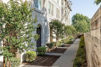 Charming exterior walkway lined with lush greenery and modern residential architecture.