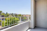 Serene townhome balcony with stunning views of lush greenery and distant hills under a clear blue sky.