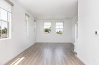 Bright and airy room with wood flooring, large windows, and stylish roller blinds, perfect for a modern living space.
