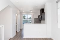 Modern open kitchen and half bath with sleek cabinetry and natural light streaming through large windows.