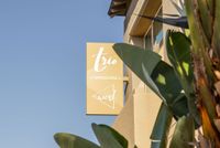 Inviting exterior view of Trio Townhomes with lush greenery and welcoming signage.