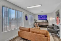 Inviting leasing office lounge with sleek leather sofa, modern decor, and bright windows overlooking cityscape.