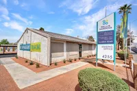Charming exterior of Nellis Gardens leasing office with well-maintained landscaping and prominent signage showcasing newly renovated 1, 2, and 3-bedroom apartments.
