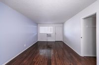 Contemporary apartment interior featuring sleek hardwood floors, softly textured walls, and natural light streaming through a large window.