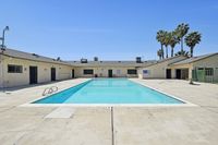 Inviting apartment complex with a sparkling outdoor pool, surrounded by palm trees and modern amenities, offering a perfect Californian lifestyle.