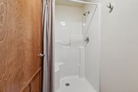 Elegant bathroom with modern enclosed shower featuring sleek fixtures and a stylish wood door accent.