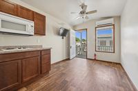 Bright and inviting apartment space featuring polished wood flooring, modern cabinets, and a stylish ceiling fan, leading to a private balcony with scenic views.