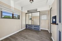 Bright room with ample storage, featuring a large mirrored wardrobe and natural light from wide windows, enhancing the elegant wood flooring.