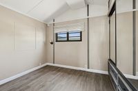 Bright and airy room with vaulted ceiling, stylish wood flooring, and a modern mirrored closet.
